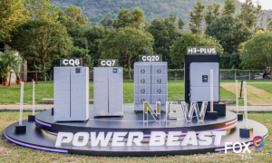 Outdoor display platform with four gray cabinets labeled CQ6, CQ7, CQ20, and H3-PLUS; large 'POWER BEAST' sign and FOX ESS logo in the corner. Outdoor display platform with four gray cabinets labeled CQ6, CQ7, CQ20, and H3-PLUS; large 'POWER BEAST' sign and FOX ESS logo in the corner.