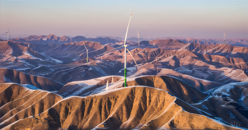 Wind turbines rise above snow-dusted desert hills at dusk, forming a wind farm across the arid landscape. Wind turbines rise above snow-dusted desert hills at dusk, forming a wind farm across the arid landscape.