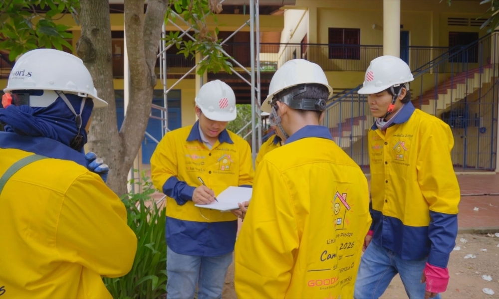 Group of workers in yellow protective jackets and white hard hats review plans outdoors near a building. Group of workers in yellow protective jackets and white hard hats review plans outdoors near a building.