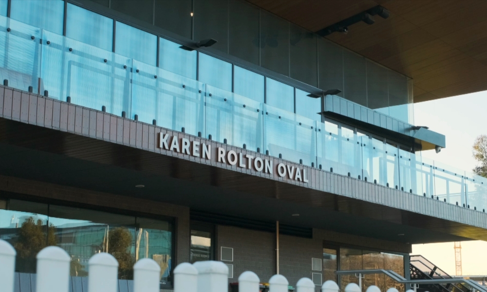 Exterior view of Karen Rolton Oval entrance with a blue-tinted glass balcony and bold white signage reading 'KAREN ROLTON OVAL' Exterior view of Karen Rolton Oval entrance with a blue-tinted glass balcony and bold white signage reading'KAREN ROLTON OVAL'