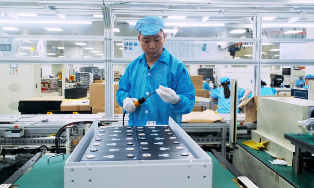 Worker in blue uniform and cap soldering components on an electronics assembly line in a clean factory. Worker in blue uniform and cap soldering components on an electronics assembly line in a clean factory.