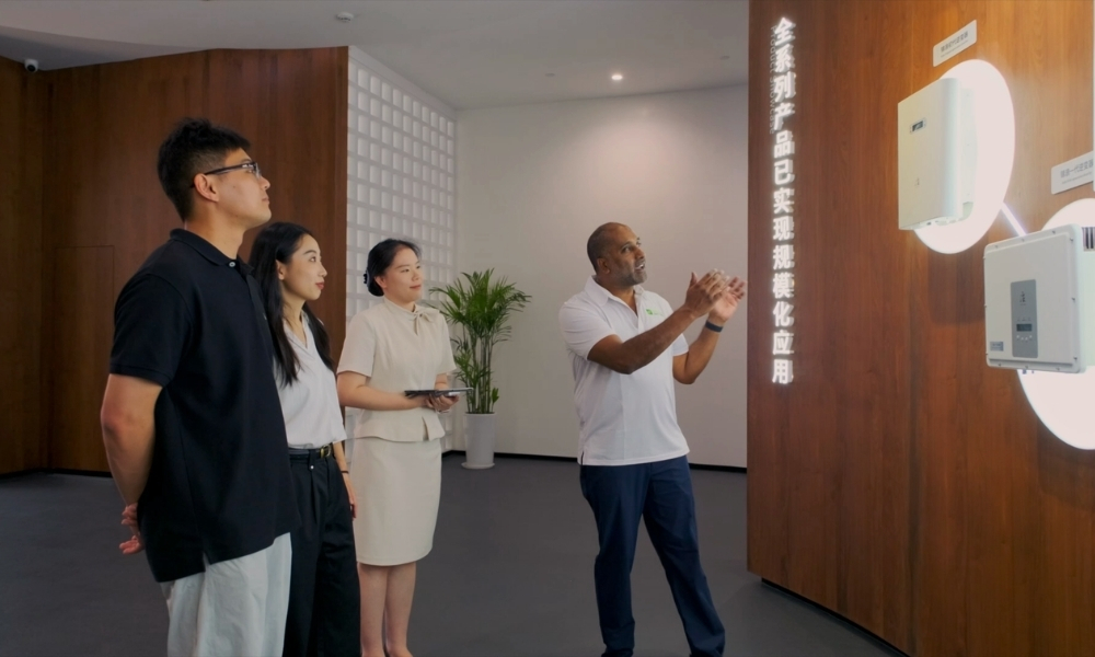 Group of four adults listening to a man explaining wall-mounted tech displays in a modern showroom. Group of four adults listening to a man explaining wall-mounted tech displays in a modern showroom.